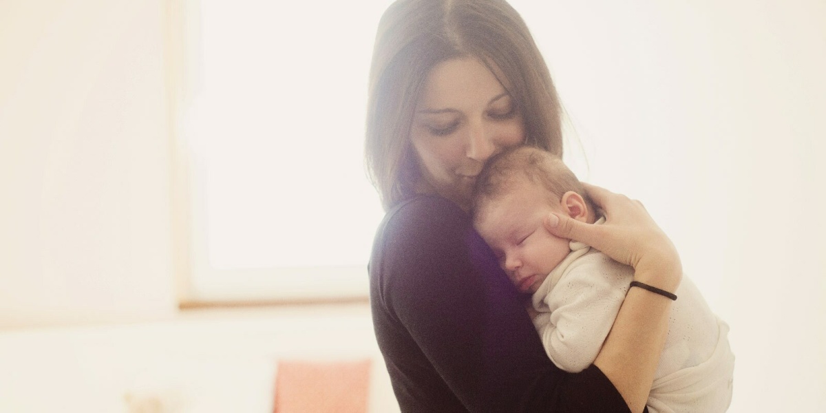 Mutter in Elternzeit hält Baby im Arm