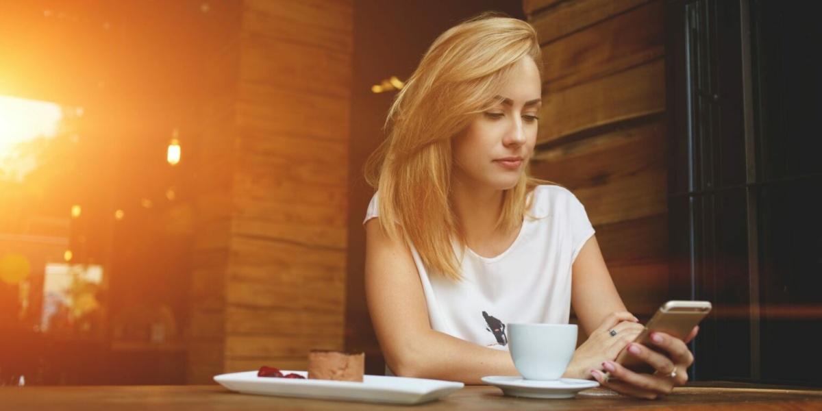 Frau schaut im Café auf ihr Firmenhandy