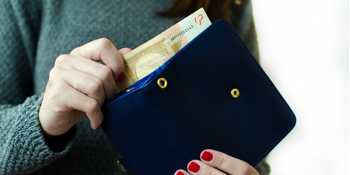 Eine Frau holt Geld aus dem Portemonnaie