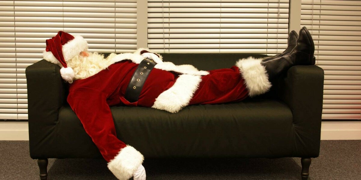 Weihnachtsmann liegt müde auf dem Sofa 